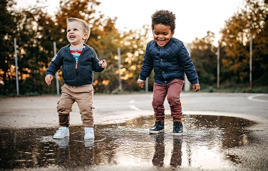 Two children jumping in puddles